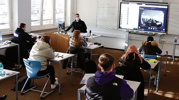 Während ein Teil der Schüler hier mit Lehrer Daniel Kleine (links) im Klassenzimmer sitzt, verfolgt der andere Teil der Gruppe den Unterricht zuhause am Rechner.